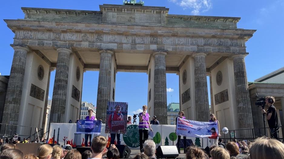 Menschen von Germanwatch bei einer Klimademo vor dem Brandenburger Tor mit Bannern und einem großen Foto von Saúl Luciano Lliuya